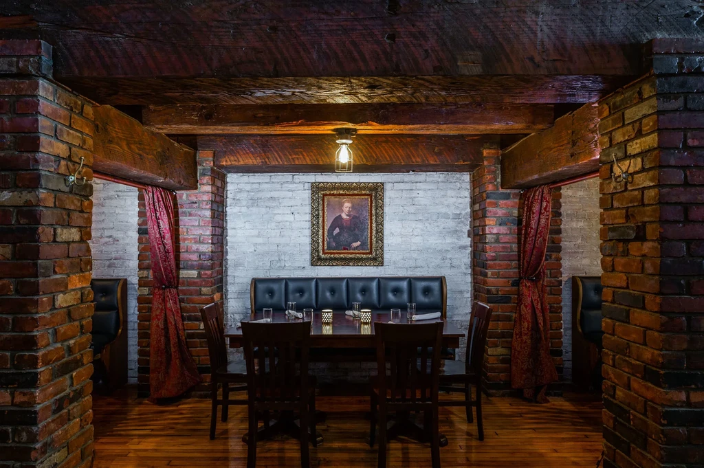 Rustic restaurant interior with exposed brick, dark wood, and set dining table.
