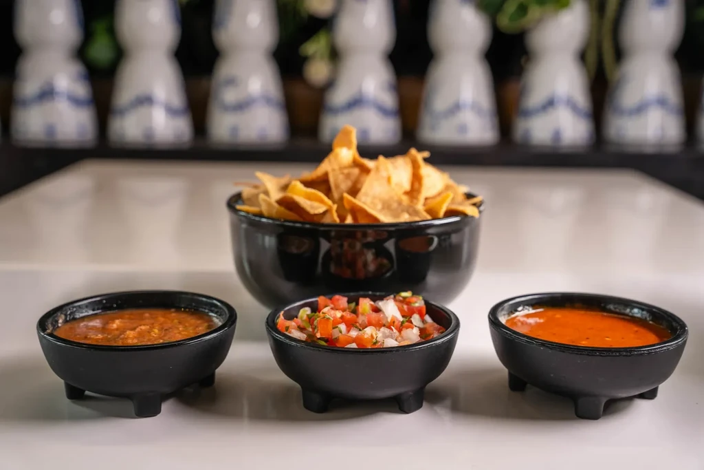 Mexican appetizers: tortilla chips, pico de gallo, and two red salsas.