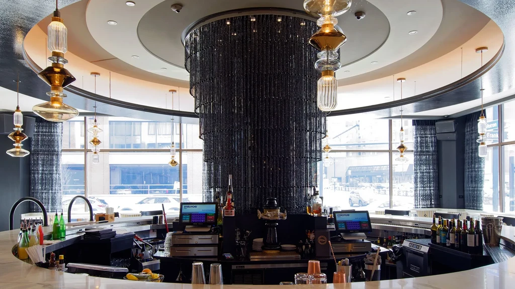 Modern upscale bar interior with circular counter and shimmering central pillar.