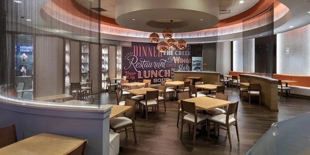 Empty modern restaurant with wood tables, orange booths, and menu mural.