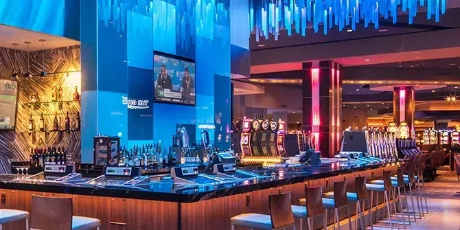 Upscale casino bar with colorful lighting, liquor, and slot machines.
