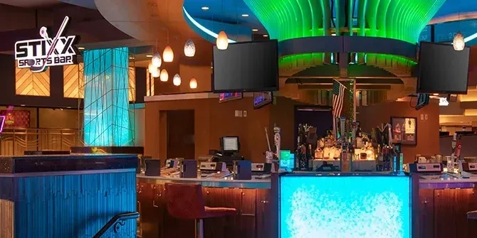 Stixx Sports Bar interior with illuminated bar, colorful lighting, and TVs.