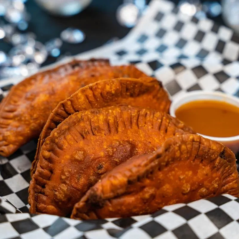 Golden-brown deep-fried pastries with crimped edges and dipping sauce.