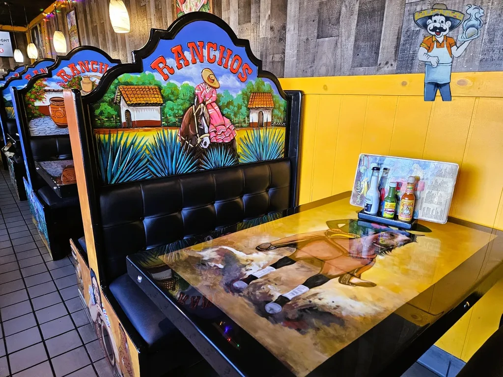 Restaurant interior featuring ornately painted Mexican-themed booths and decor.