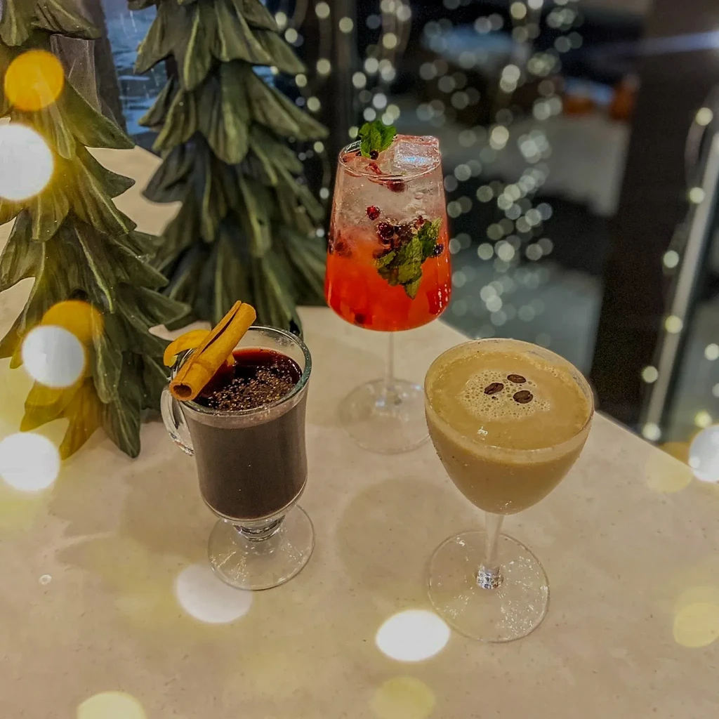 Three festive drinks: mulled, fizzy red, creamy brown, with holiday decor.