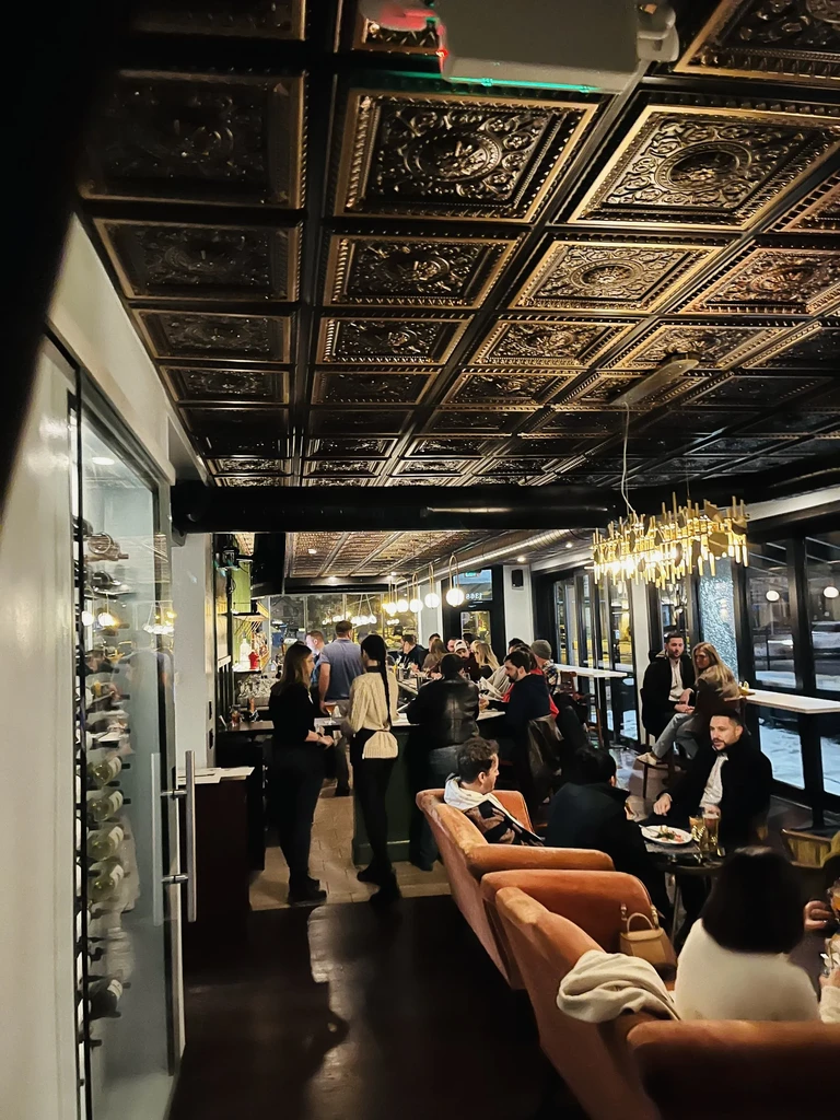 Ornate pressed tin ceiling above a dimly lit, busy restaurant interior.