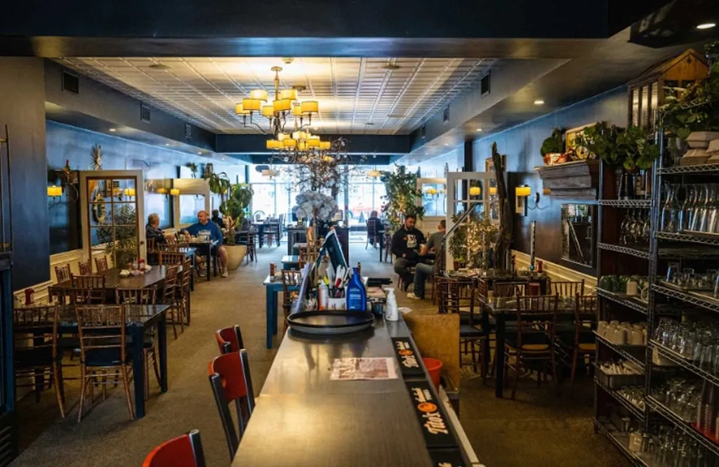 Warmly lit restaurant interior with bar, dining tables, and seated patrons.