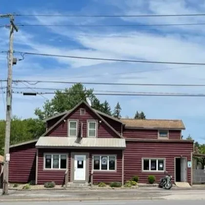 Two-story log-style building with a dark motorcycle parked outside.