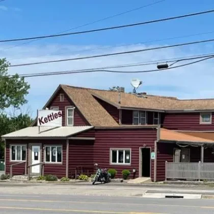 Rustic red Kettles building with a dark motorcycle parked in front.
