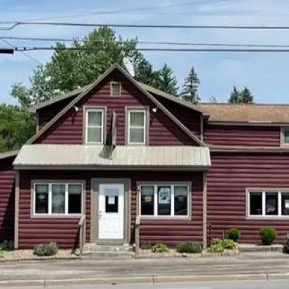 Rustic two-story building with brown siding and a gabled roof.
