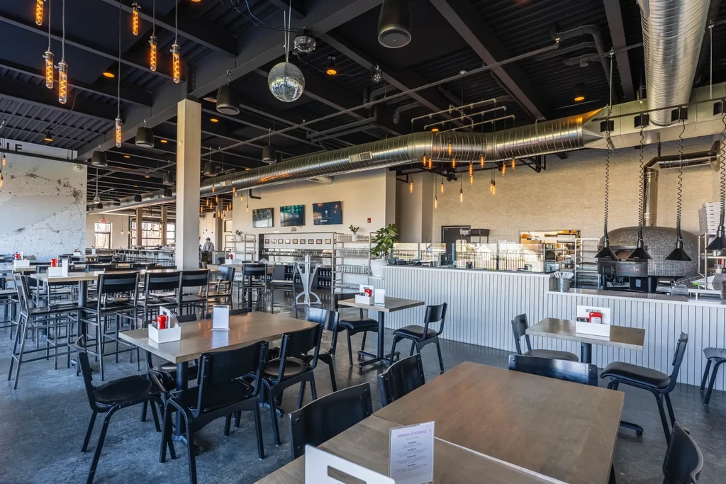 Modern industrial-chic restaurant interior with dining area and mosaic pizza oven.