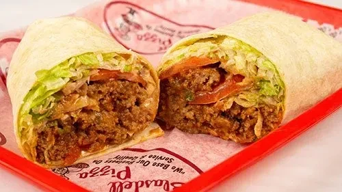 Savory burrito half with meat, lettuce, tomato, on 'Slasdell Pizza' paper.