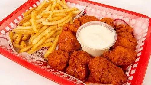 Boneless buffalo chicken, fries, and dip in a red checkered basket.