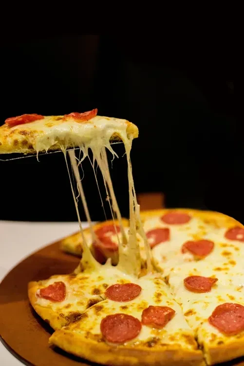 Pepperoni pizza with a slice lifting, showing a long cheese pull.
