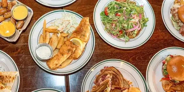 Overhead view of a table with fried fish, fries, and multiple dishes.