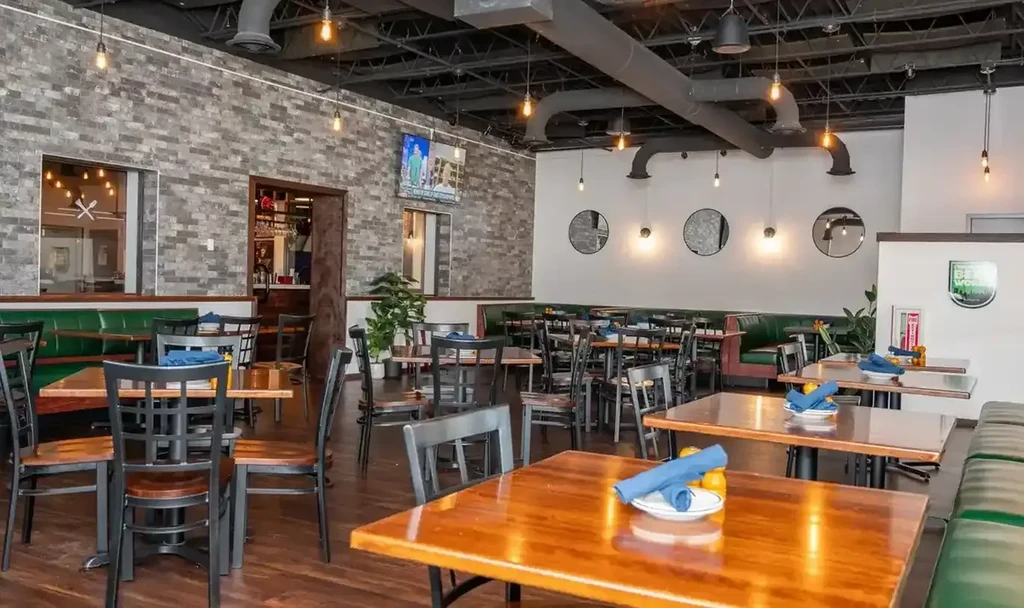 Empty modern industrial restaurant interior with booths, bar, and Beer World sign.