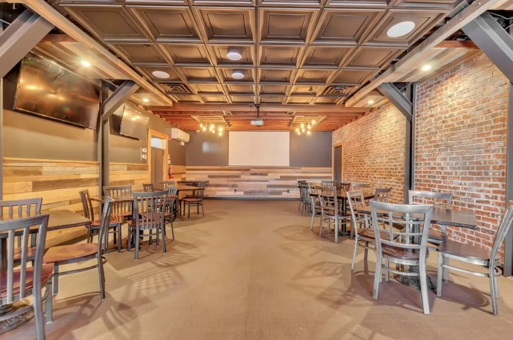 Empty industrial-rustic restaurant and event space with screen.