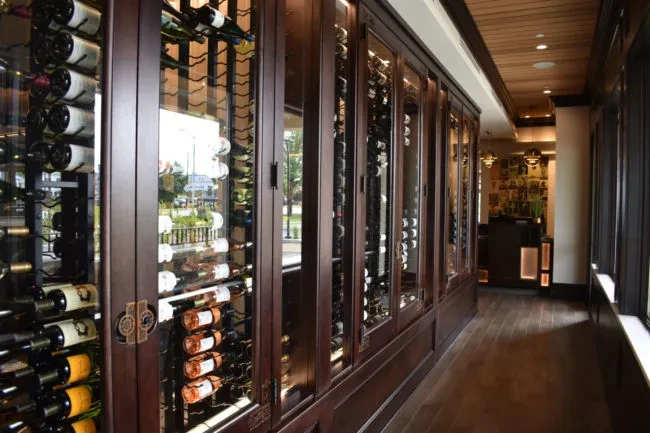 Long restaurant hallway with an extensive, glass-fronted wine cellar.