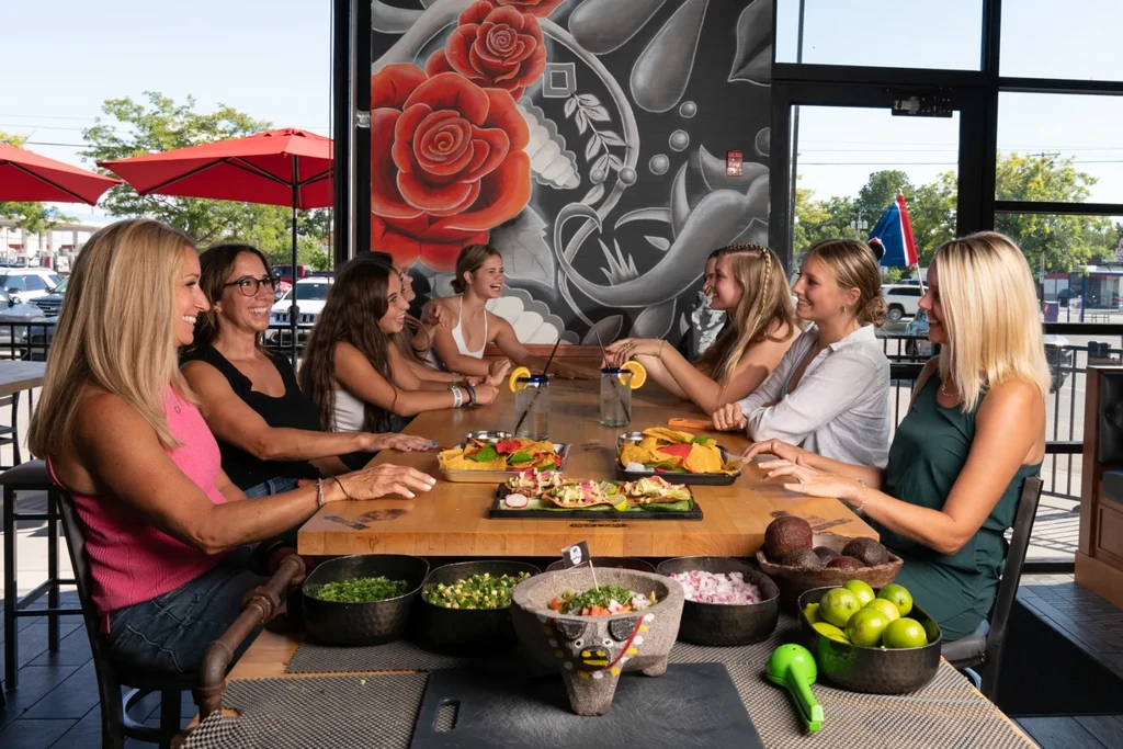 Seven women enjoy Mexican food and drinks in a vibrant restaurant.