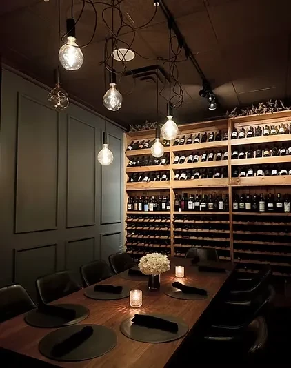 Elegant private dining room with wooden table, wine rack, and warm lighting.