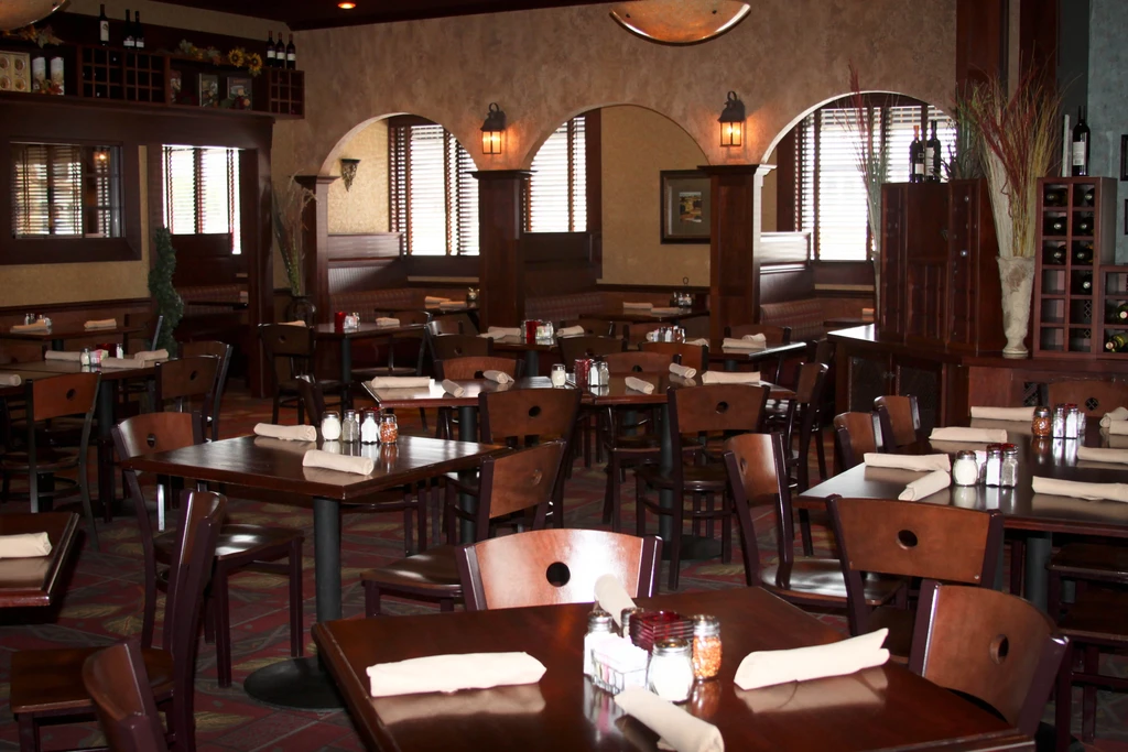 Warm, empty restaurant dining room with set tables and wooden decor.