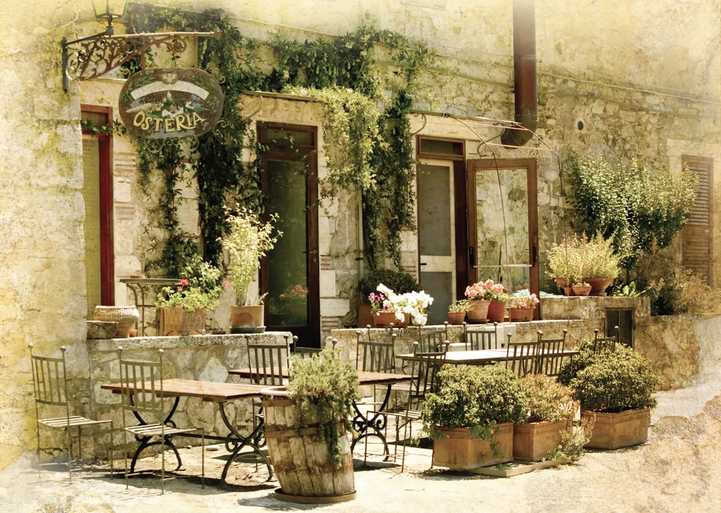 Rustic stone osteria exterior covered in green vines with outdoor seating.