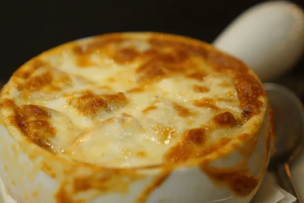 Top-down view: dish with bubbly, browned cheese in white bowl.