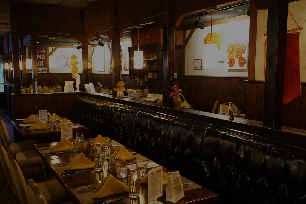 Cozy, rustic restaurant dining room with dark wood tables and tufted banquette.