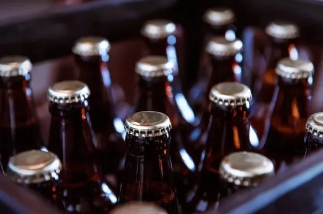 Close-up of dark brown bottles with crown caps in a carrier.