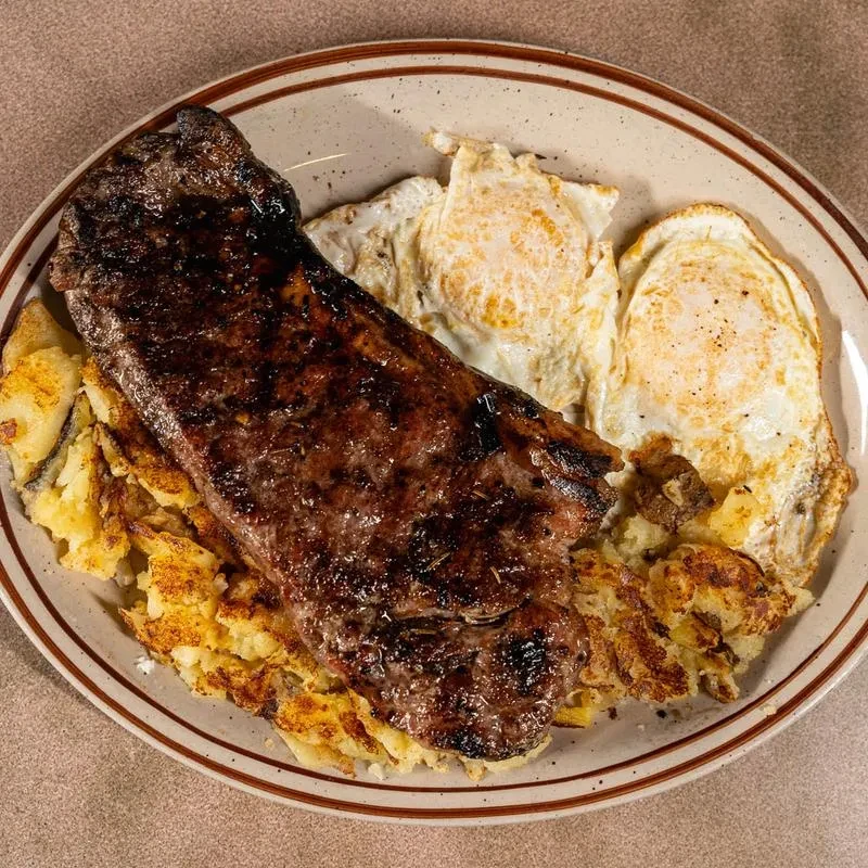 Well-plated grilled steak, fried eggs, and crispy hash browns.