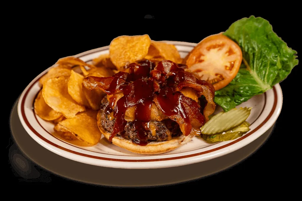Top-down burger with bacon, cheese, chips, lettuce, tomato, pickles.
