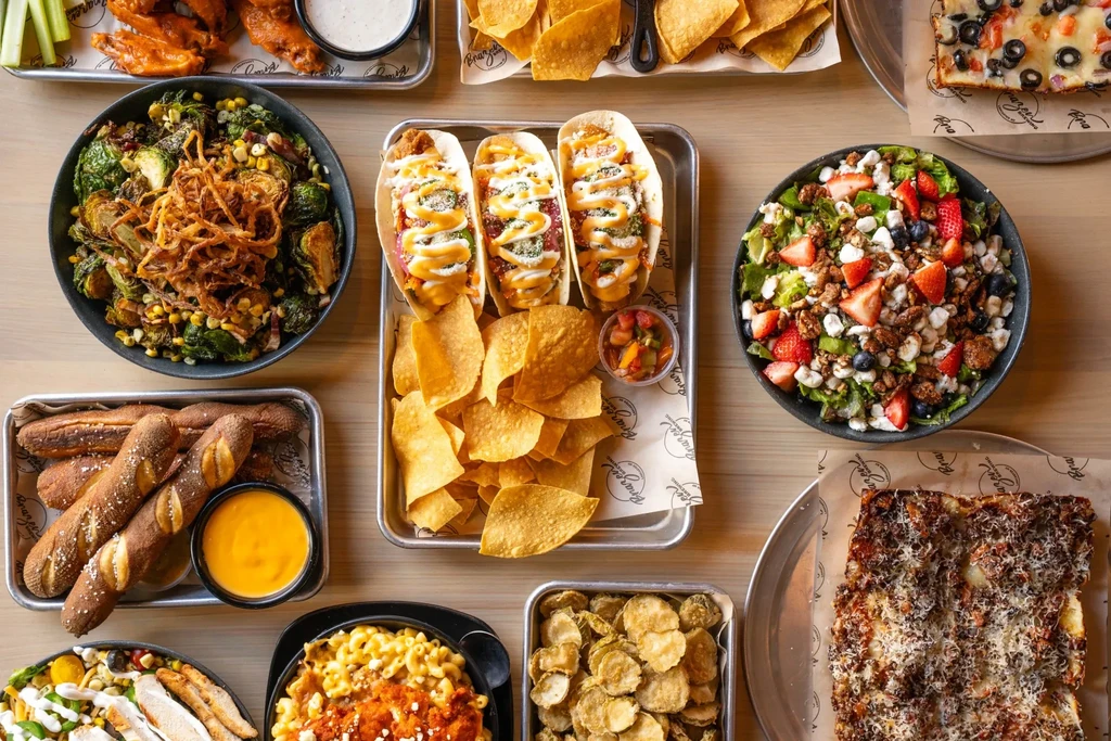 Overhead view of a table laden with many Brazen Burger Co. dishes.