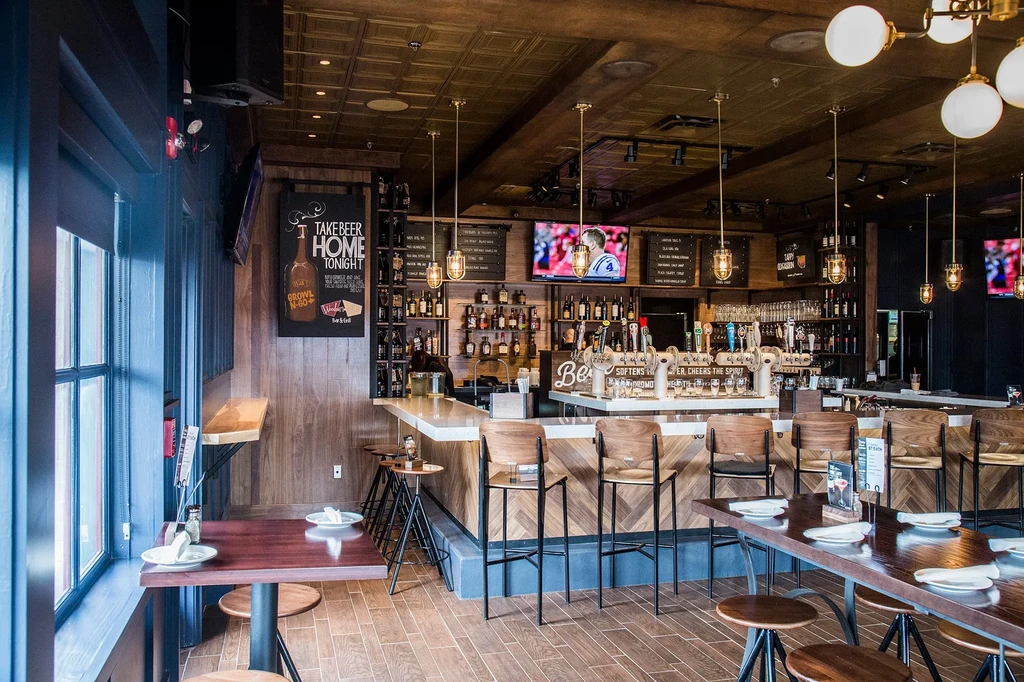 Modern upscale bar with beer taps, sports TVs, warm wood, and seating.