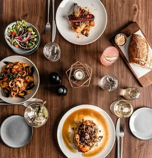 Overhead view of a gourmet dining table with various food and drinks.