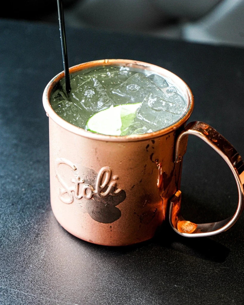 Close-up of Stoli copper mug drink with ice, lime, and straw.