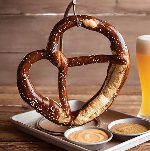 Golden-brown pretzel, cheese sauce, grainy mustard, and a beer.