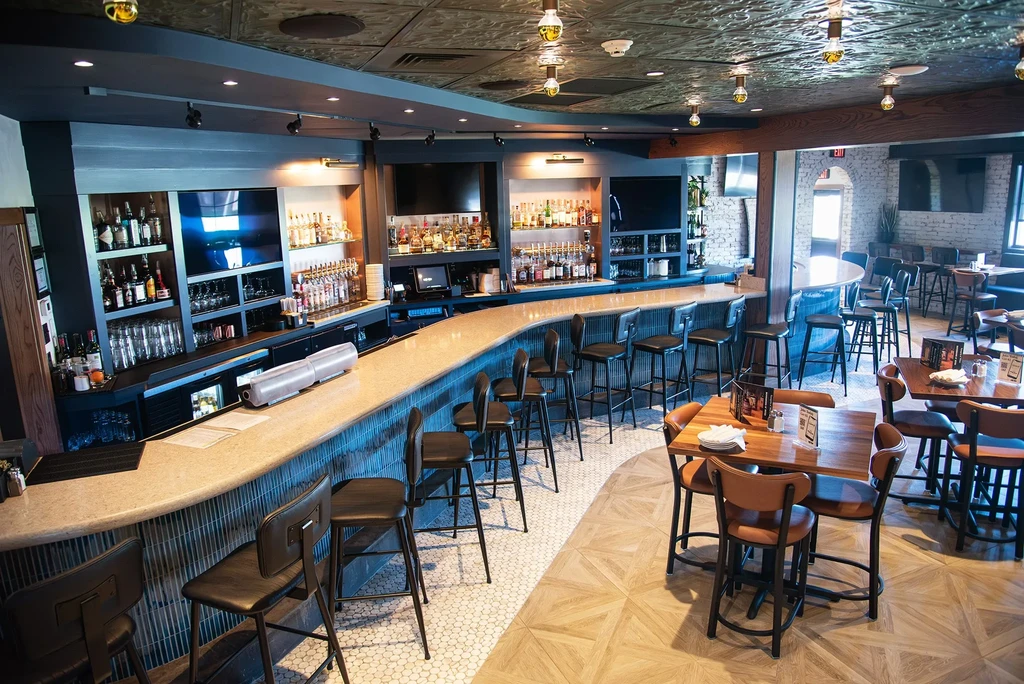 Empty modern restaurant interior with a long curved bar and dining.