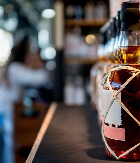 Close-up of amber liquor bottle with rustic string wrap, blurred bar.