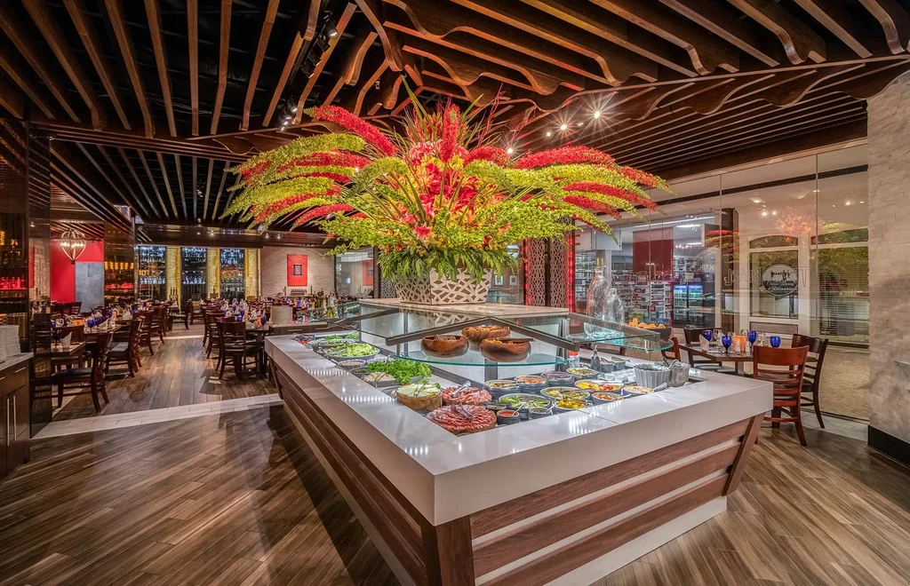 Modern upscale restaurant with colorful salad bar and vibrant floral centerpiece.