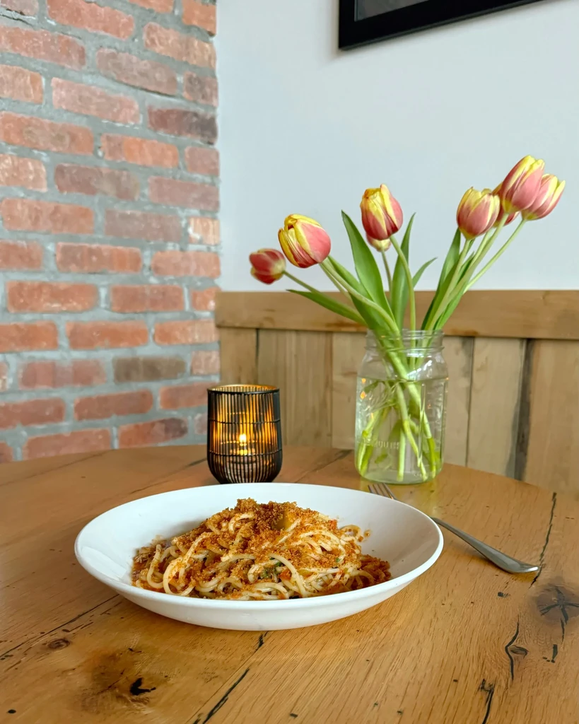 Spaghetti with breadcrumbs and red sauce on a rustic wooden table.
