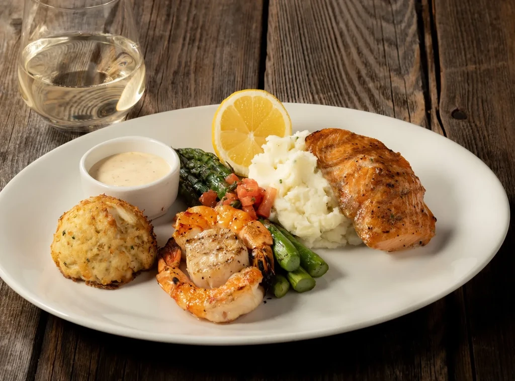 Seafood dish: salmon, crab cake, shrimp, scallop, mashed potatoes, and asparagus.