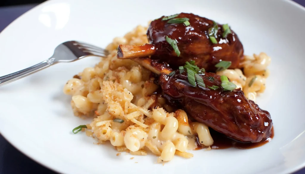 Macaroni and cheese with sauced meat, breadcrumbs, herbs, and a fork.