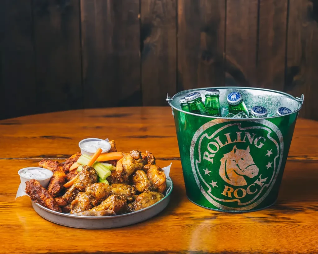 Platter of chicken wings, celery, sauces, and Rolling Rock beer.