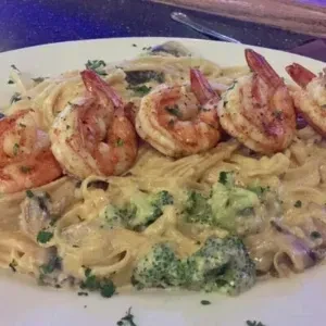 Creamy pasta with grilled shrimp, broccoli, mushrooms, and parsley.