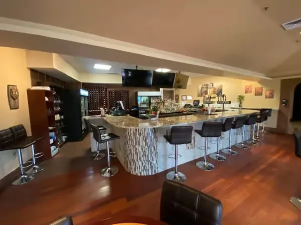 Empty modern bar with mosaic tile counter, liquor, and bar stools.