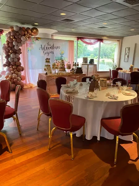 Celebration setup with "The Adventure Begins" backdrop, desserts, and balloon arch.
