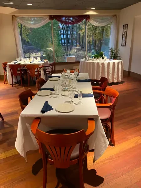 Empty restaurant dining room, set tables, chairs, and window view.