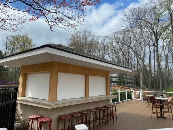 Outdoor bar and wooden deck nestled in a bare forest with pink blossoms.