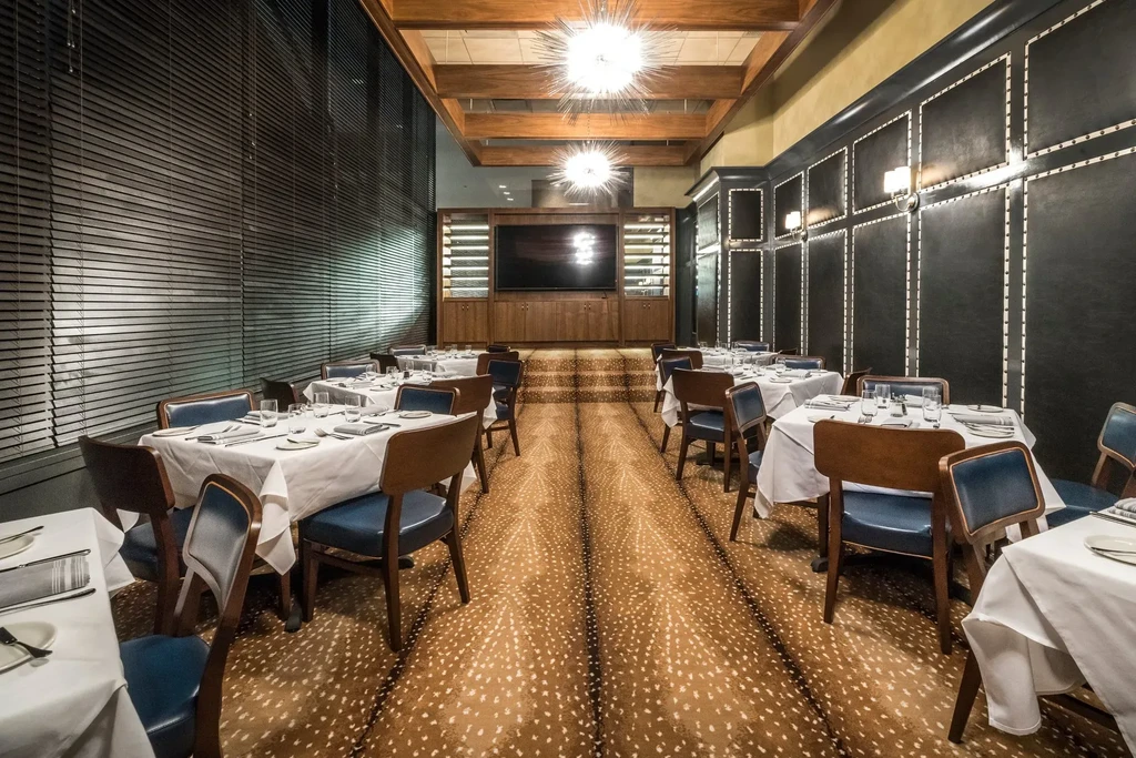 Restaurant dining room with set tables, spiky chandeliers, and spotted carpet.