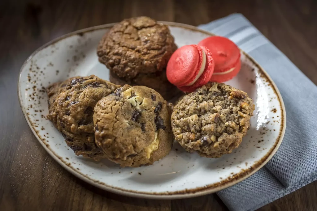 Ceramic plate piled high with cookies and two bright red macarons.